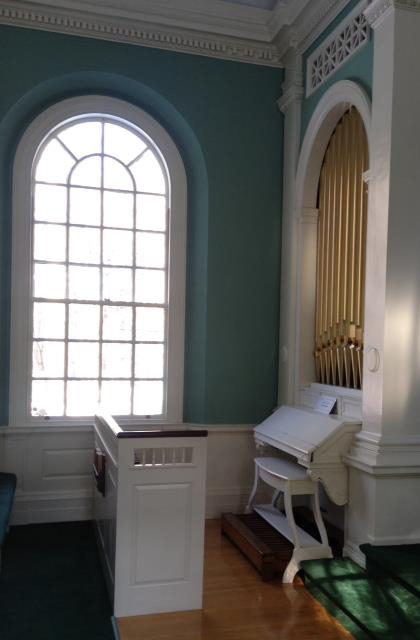 A room with a large window and a piano.